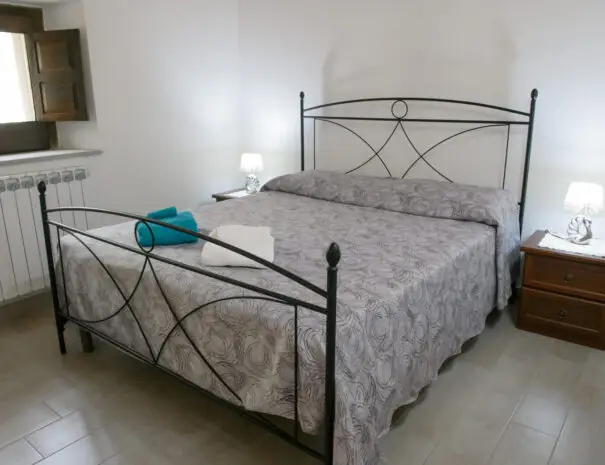 Camera da letto matrimoniale rustica con letto in ferro battuto e travi a vista a Nova Siri