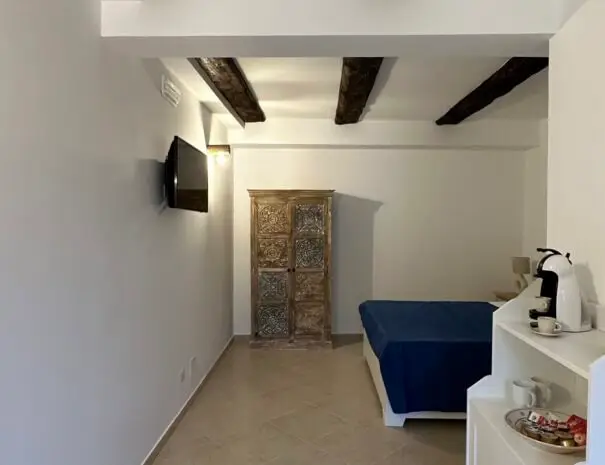 Camera matrimoniale moderna con travi a vista e TV a schermo piatto a Nova Siri
