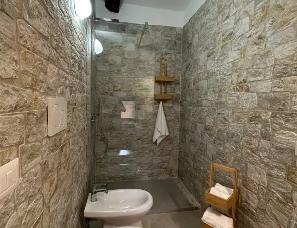 Bagno moderno con pareti in pietra e doccia in vetro al B&B Nova Siri