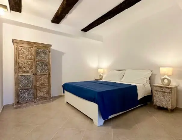 Camera da letto elegante con armadio intarsiato e soffitto rustico a Nova Siri