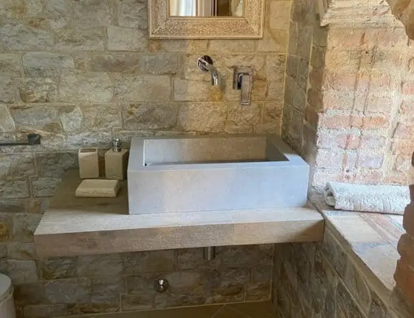 Bagno rustico con pareti in pietra naturale e specchio intarsiato a Nova Siri