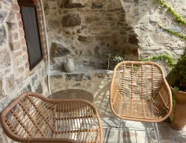 Area esterna con sedie in vimini e pareti in pietra a Nova Siri